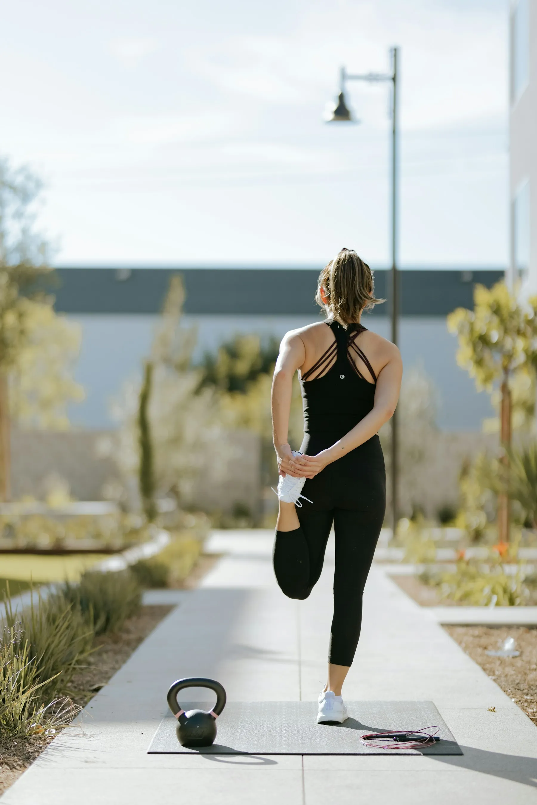 A person moving through a standing stretch on a mat outdoors
