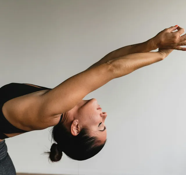 A woman reaching both arms overhead in a long standing stretch