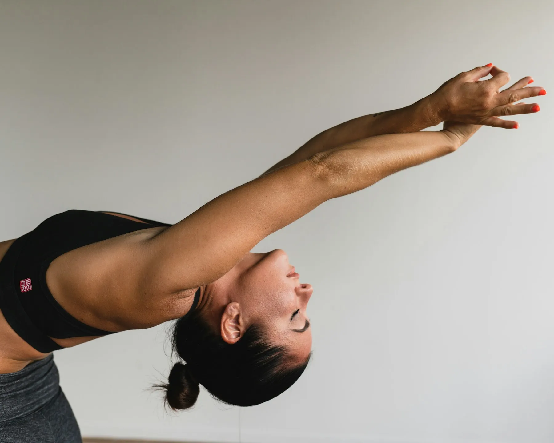 A woman reaching both arms overhead in a long standing stretch