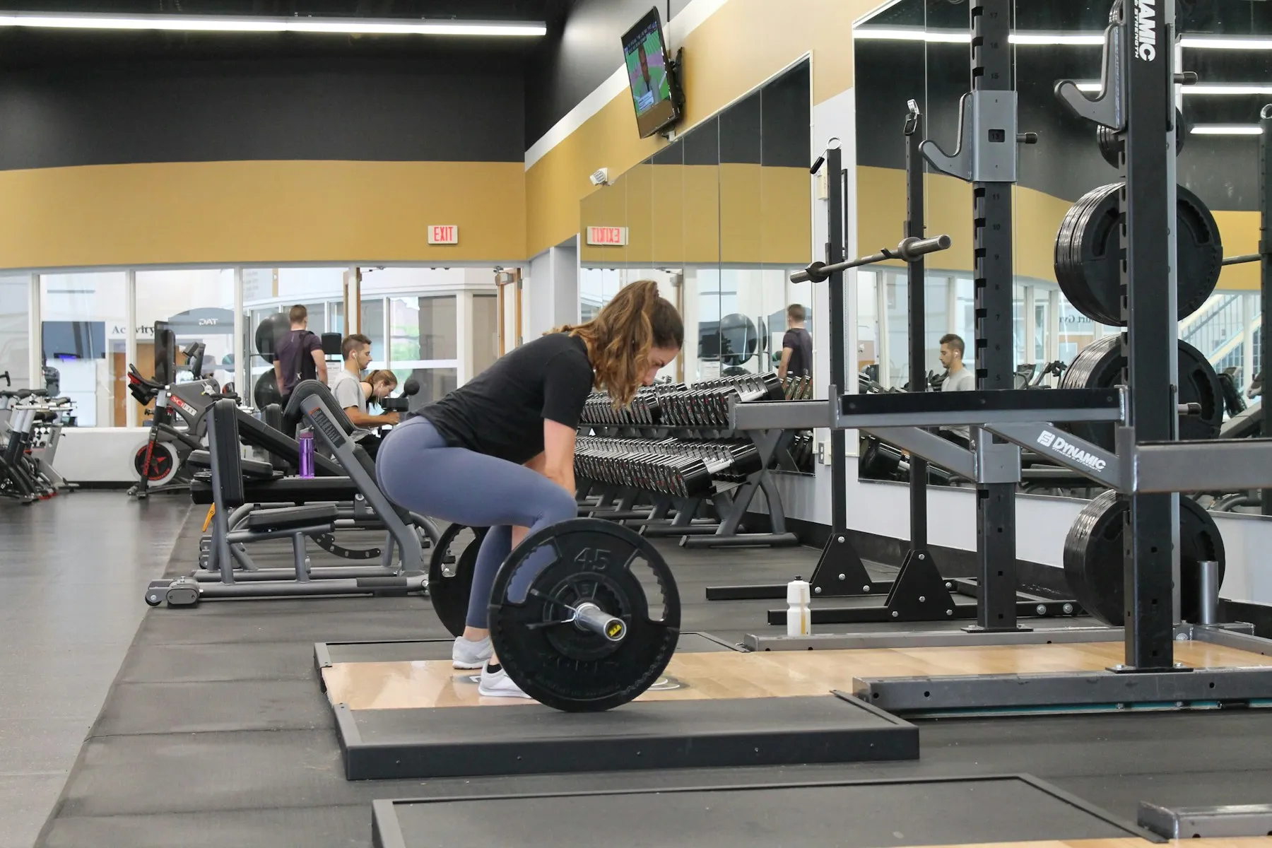 A woman setting up over a loaded barbell on a gym platform