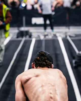An athlete seen from behind, head lowered, facing an empty track