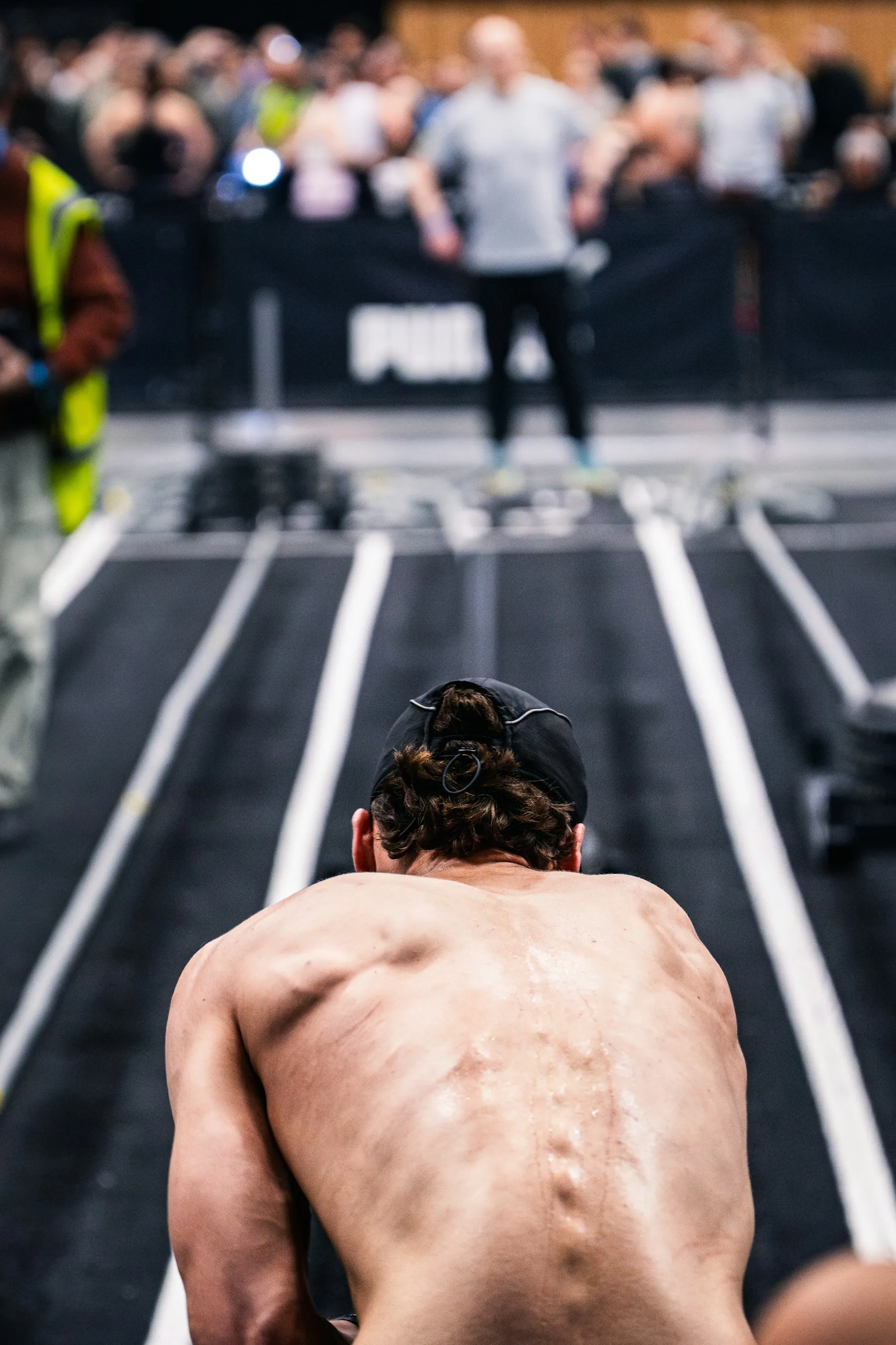 An athlete seen from behind, head lowered, facing an empty track