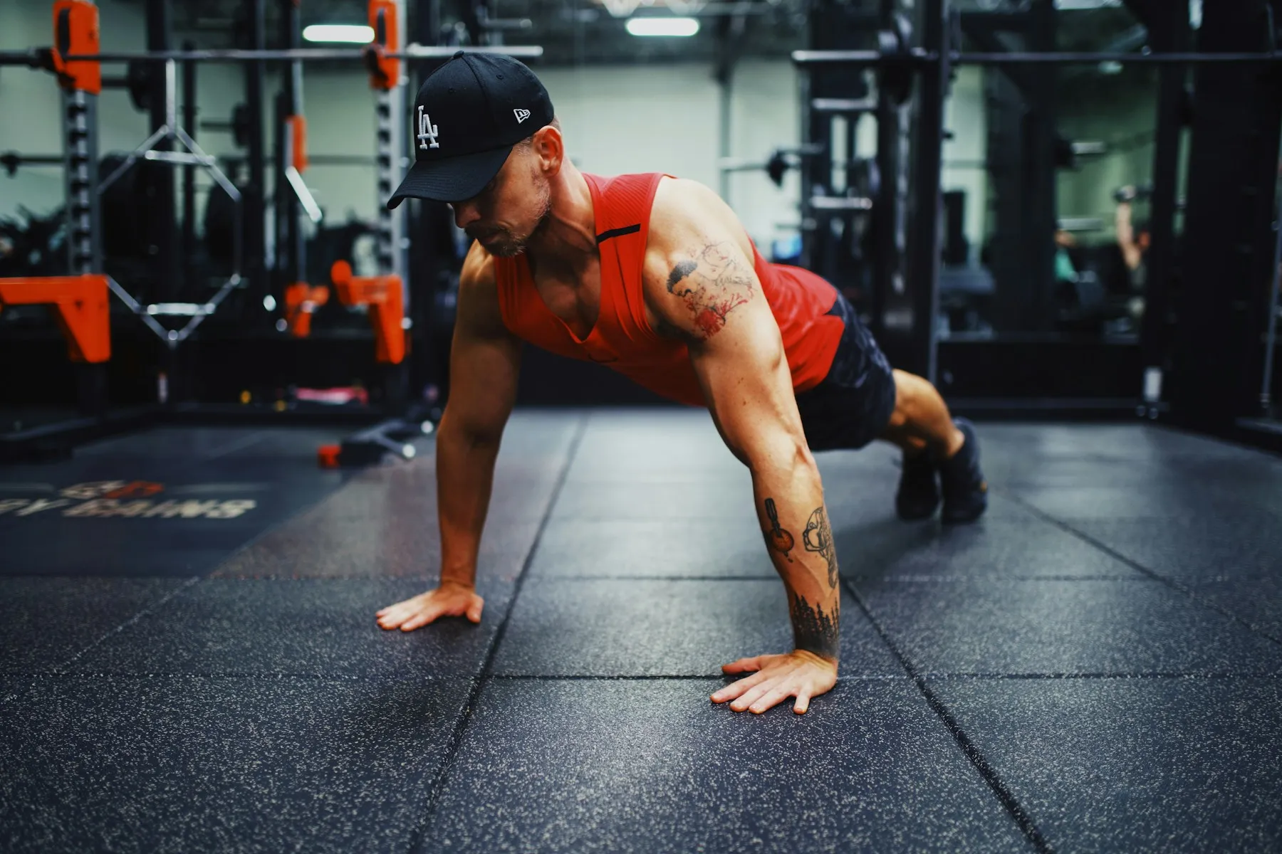A man holding the top position of a push-up on a gym floor