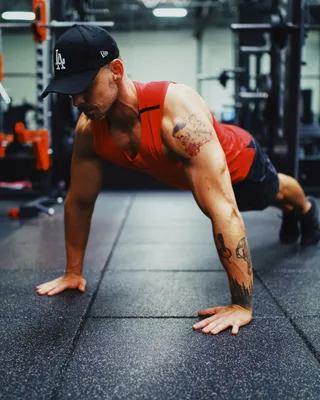 A man holding the top position of a push-up on a gym floor